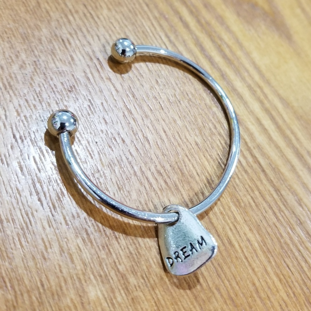 Silver colored bangle with "DREAM" charm